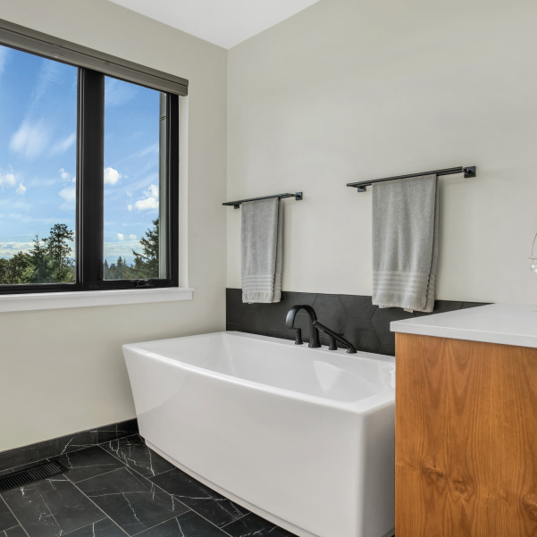 Striking white-and-black bathroom featuring a full tub in a modern home built by Mike Riddle Construction Striking white-and-black bathroom featuring a full tub in a modern home built by Mike Riddle Construction