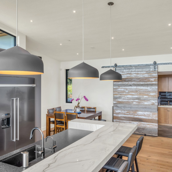 Sliding barn door and marble sit-up kitchen island in a modern kitchen built by Mike Riddle Construction Sliding barn door and marble sit-up kitchen island in a built by Mike Riddle Construction
